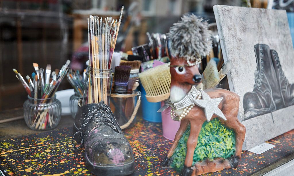 Schaufensterdeko eines Ateliers: Pinsel im Glas, Schuh, Bambi-Figur, Gemälde