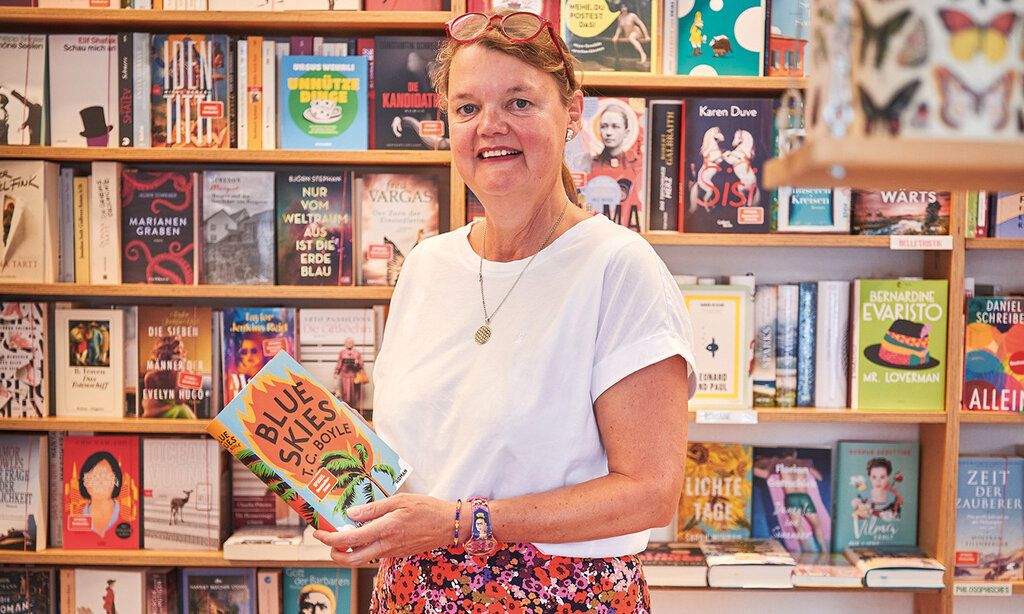 Brigitte Klasen von der Regenbogen-Buchhandlung steht vor Bücherregalen