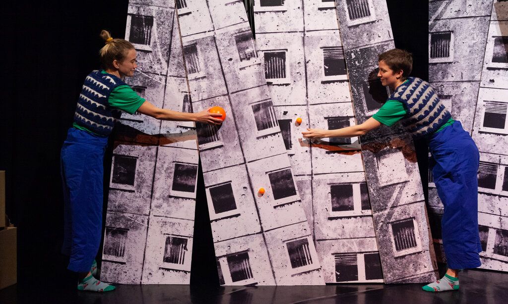 Zwei Schauspielerinnen spielen auf der Bühne mit orangen Kugeln