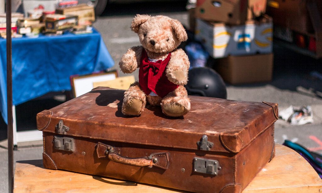Ein alter Teddybäar sitzt auf einem alten Lederkoffer