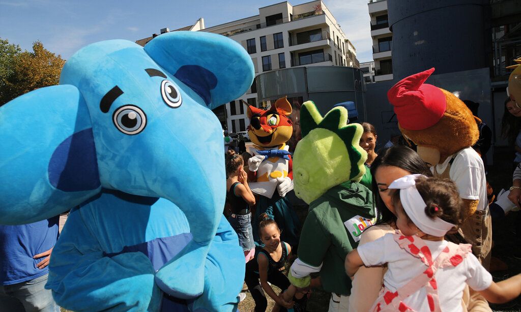 Der blaue Elefant vom Kinderschutzbund und andere verkleidete Figuren in einer Gruppe von Eltern und Kindern, auf der Wiese vorm Landtag