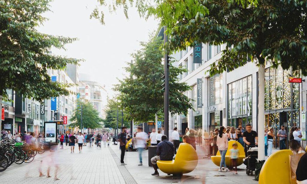 Die belebte Fußgängerzone auf der Schadow Straße im Sommer, gelbe Sitzelemente rechts im Bild