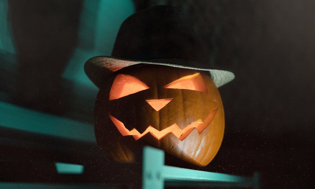 geschnitzter Halloween-Kürbis mit Hut im Dunklen