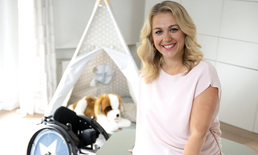 Porträt von Karoline Peter, im Hintergrund ein Spielzelt mit Plüschhund und ein Kinderrollstuhl