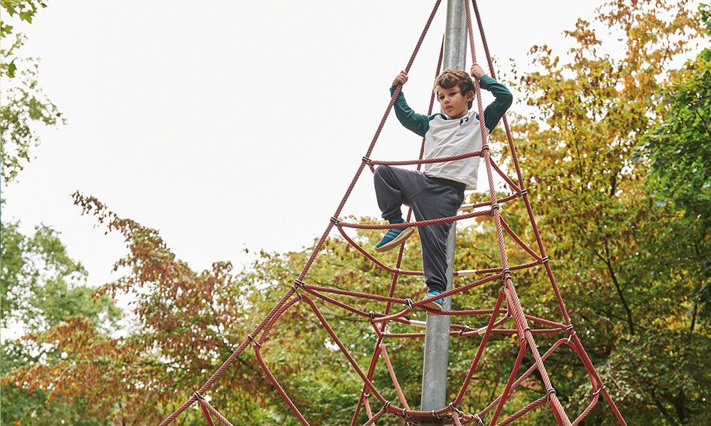Kind klettert auf einem Klettergerät auf einem Spielplatz in Oberbilk