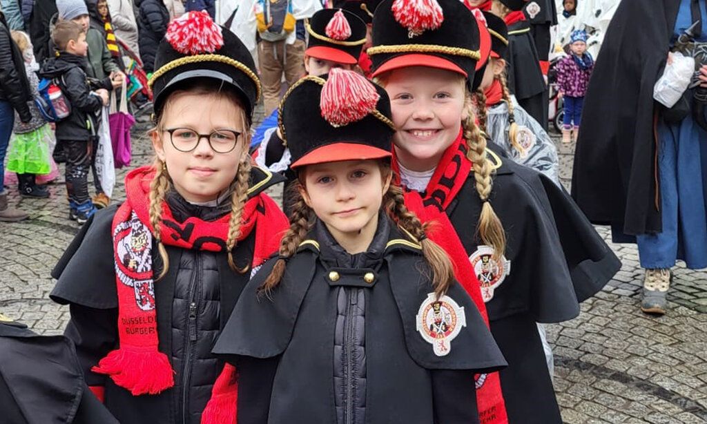 Drei Mädchen in Kostümen der Düsseldorfer Bürgerwehr beim Rosenmontagszug