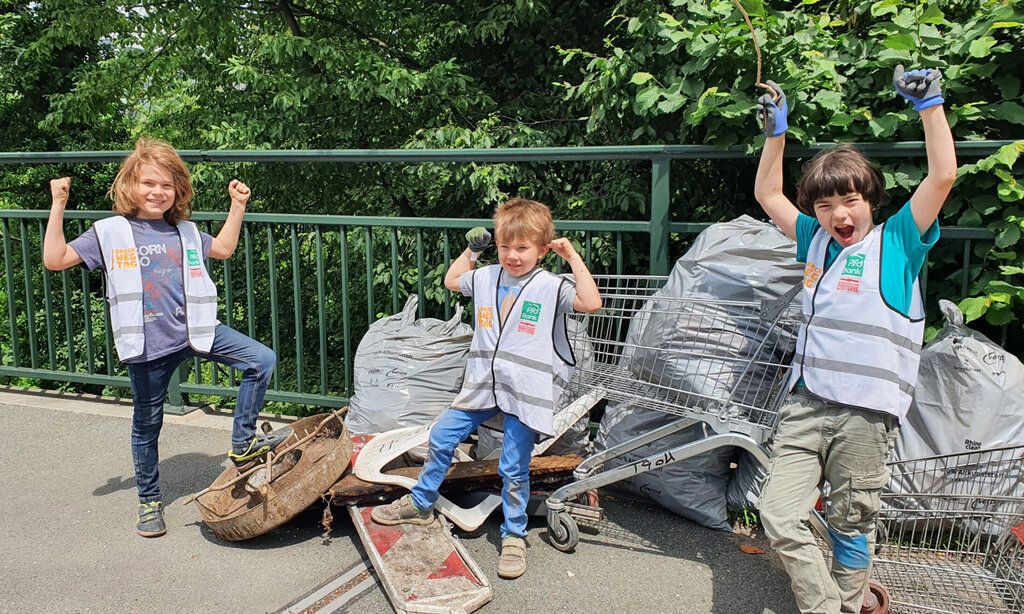 drei Kinder beim Müllsammeln am Dreck weg Tag