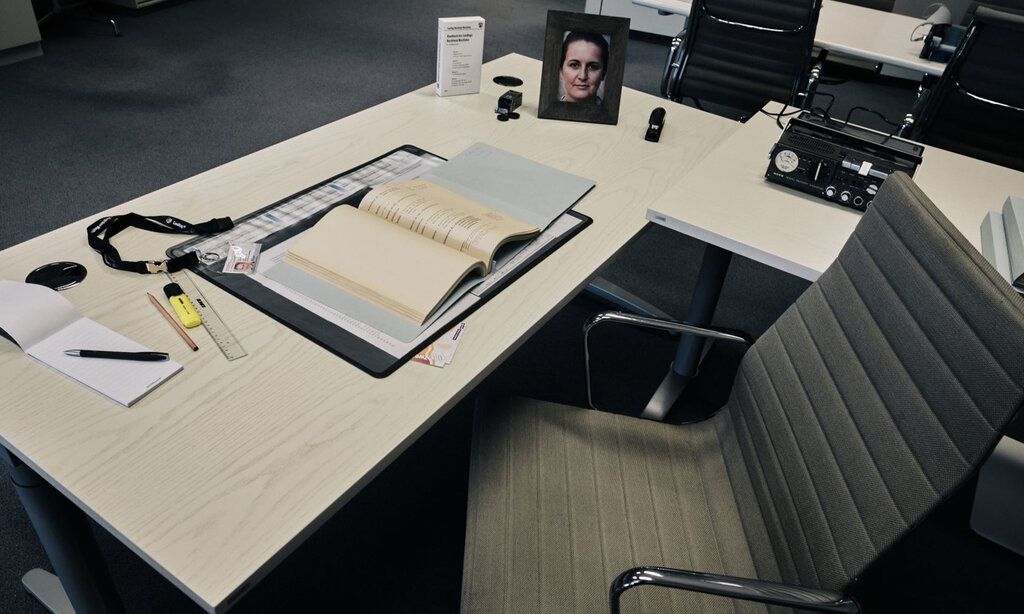 Schreibtisch in einem Bürozimmer, graue Stimmung, Bild mit Frauenporträt auf dem Tisch