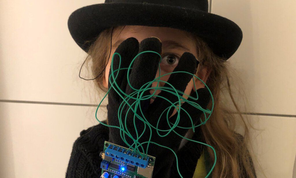 Frau mit Hut trägt Handschuh mit Verkabelungen