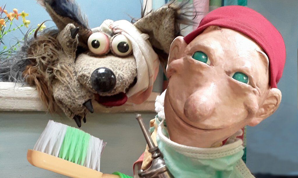 Kasperle und der Wolf stehen vor dem Bühnenbild