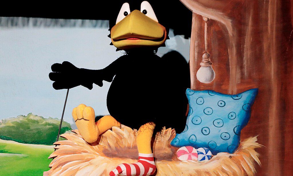 Die Puppe des kleinen Rabe Socke sitzte auf einem Nest mit Kissen.