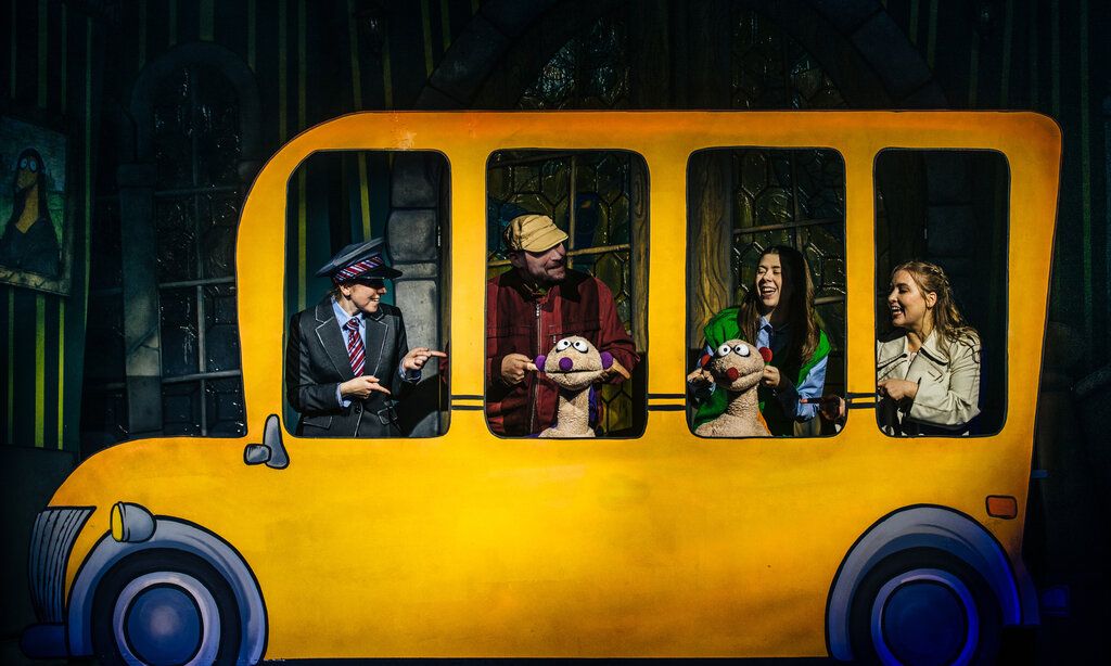 Die Puppen Jan & Henry mit Schauspielern in einem gelben Bus auf der Bühne