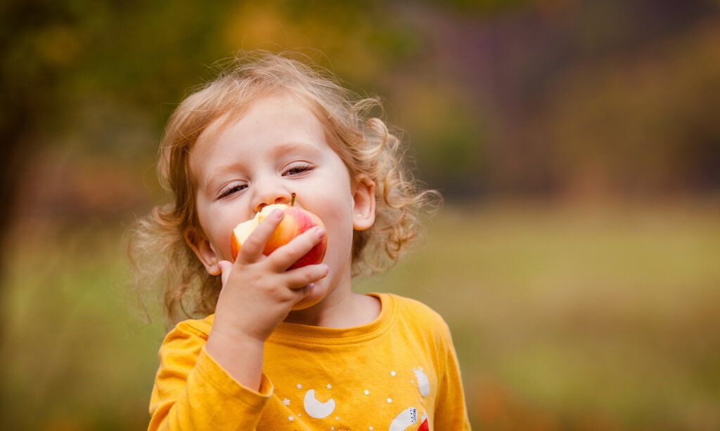 Kleines Mädchen isst leckeren roten Apfel