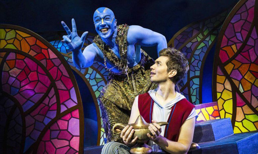 Der Dschinni aus der Wunderlampe steht lachend neben Aladin, der die Wunderlampe in der Hand hält.