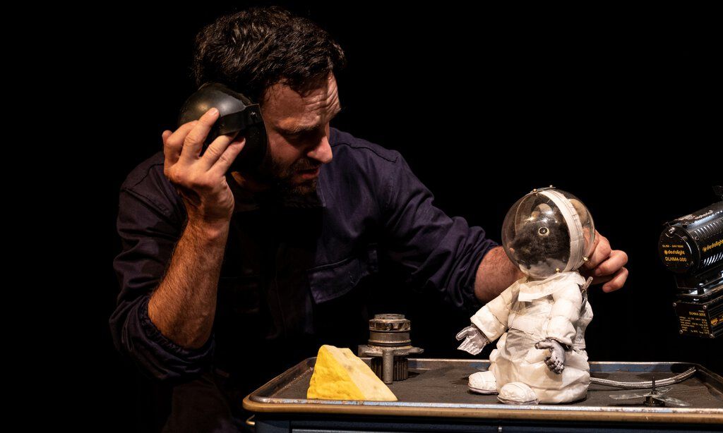 Szene aus dem Puppentheater „Armstrong“ mit der Maus Armstrong in einem Raumanzug im Gespräch mit dem Schauspieler Leo Mosler 