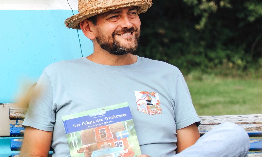 Autor Ben Walleborn sitzt mit einem Buch auf einer Parkbank 