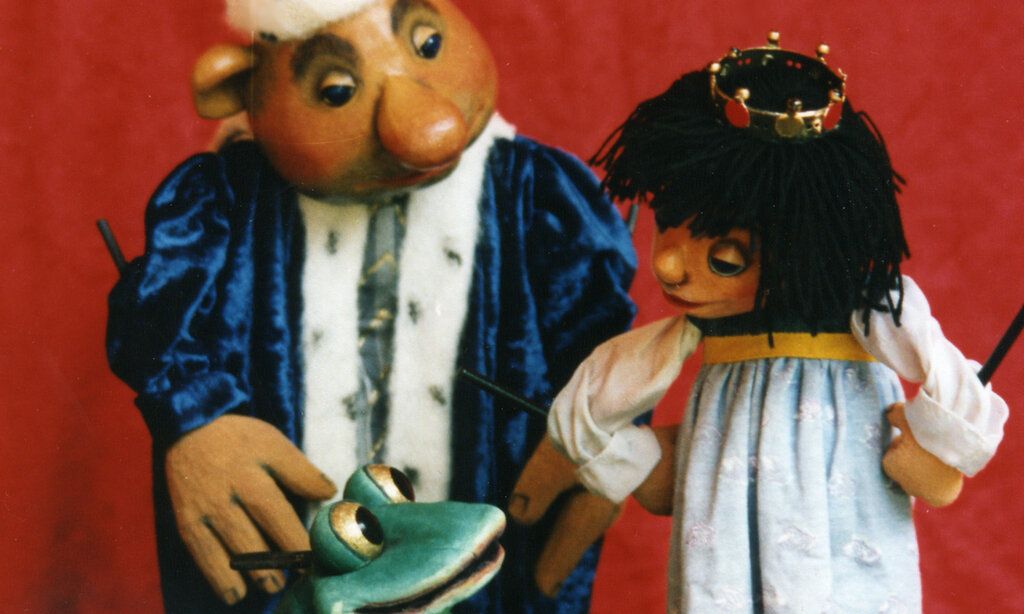 Die Hauptdarsteller aus dem "Froschkönig" als Puppen vor einer roten Wand