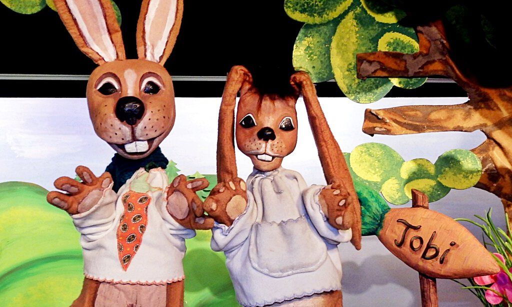 Zwei Hasenpuppen mit weißen Pullovern auf der Bühne des Puppentheaters Helmholtzstrasse.