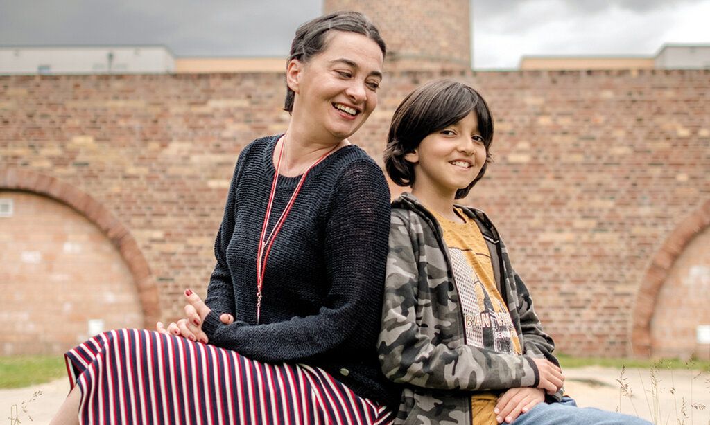 Mutter und Sohn sitzen vor altem Industriegebäude