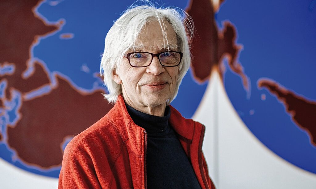 Günther Haverkamp sitzt vor einer Weltkarte