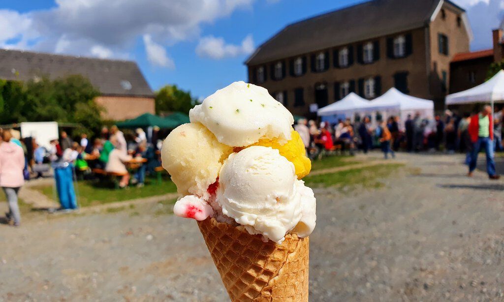 Eine große Eiswaffel wird ins Bild gehalten mit einem Fest im Hintergund 