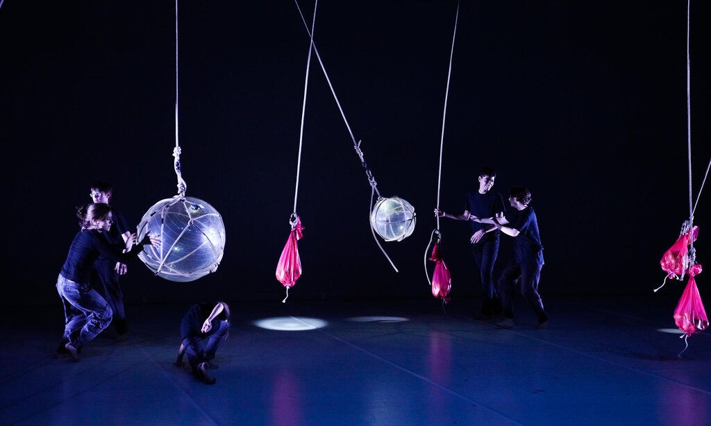 Jugendliche experimentieren auf einer Bühne mit verschiedenen schwingenden Objekten