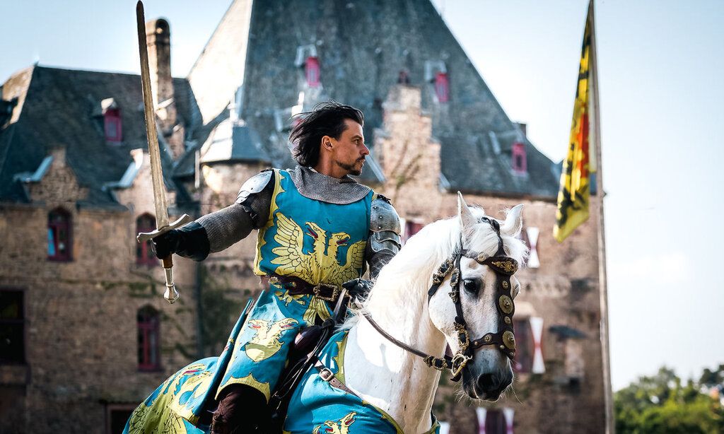 Ritter reitet auf seinem Pferd vor Burg Satzvey