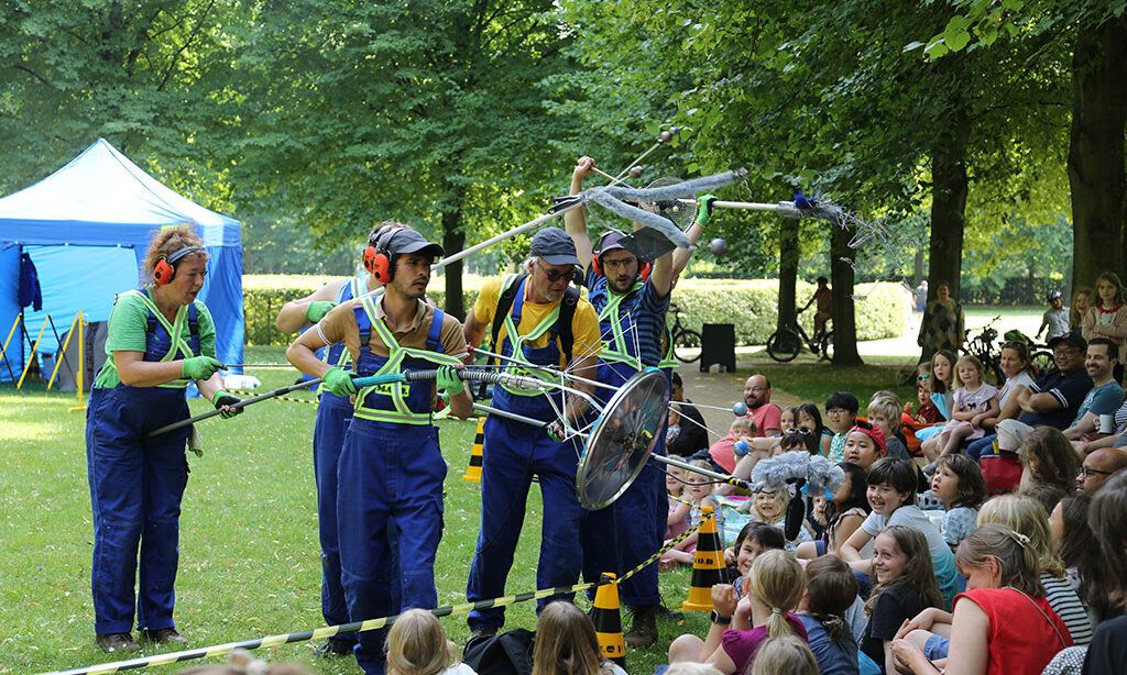 Schauspieler spielen im Park vor einer Gruppe Kinder