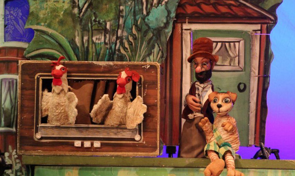 Bühnenbild des Figurentheaters Köln mit Pettersson und Findus vor ihrem Haus, zusammen mit zwei Hühnern die aus einem alten Radio schauen.