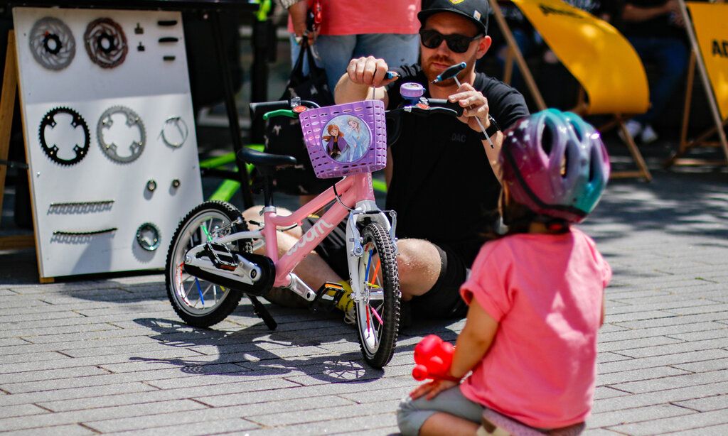 Mann prüft Kinderfahrrad, Kind guckt zu