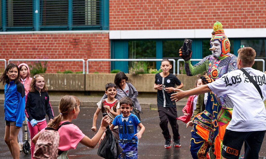 verkleideter Künstler spielt mit Kindern beim Artistik Festival