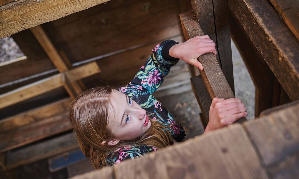 ein Mädchen klettert auf dem ASP Eller in einem Holzhaus