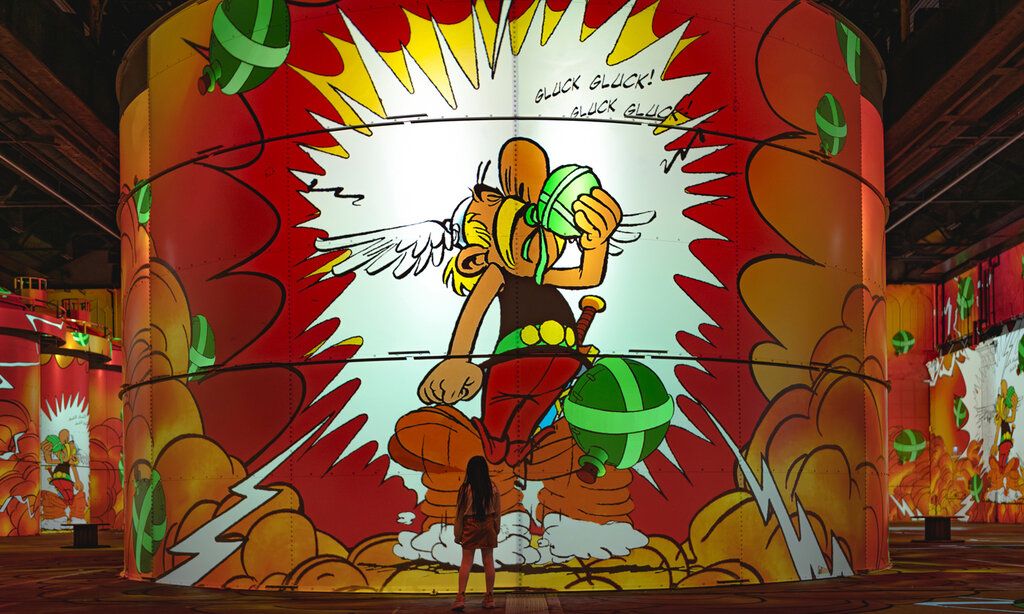 Asterix und Obelix immersive Ausstellung, Projektion von Asterix auf eine Säule, eine Frau steht klein davor