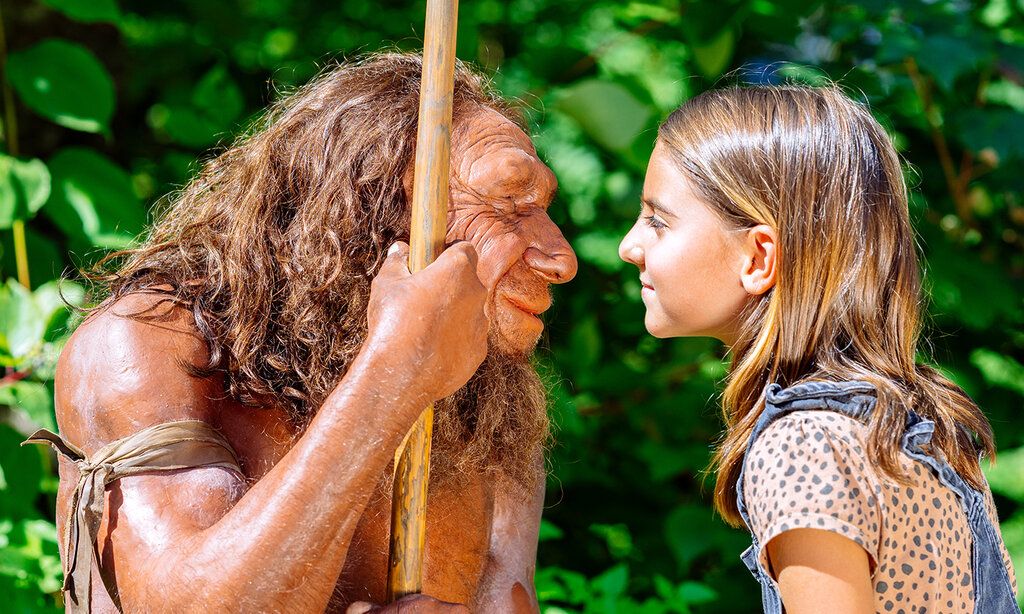 Kleines Mädchen steht dem Neandertaler gegenüber und schaut ihm in die Augen