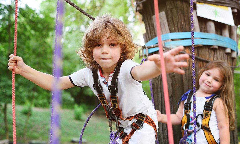 Zwei Kinder klettern in einem Hochseilgarten