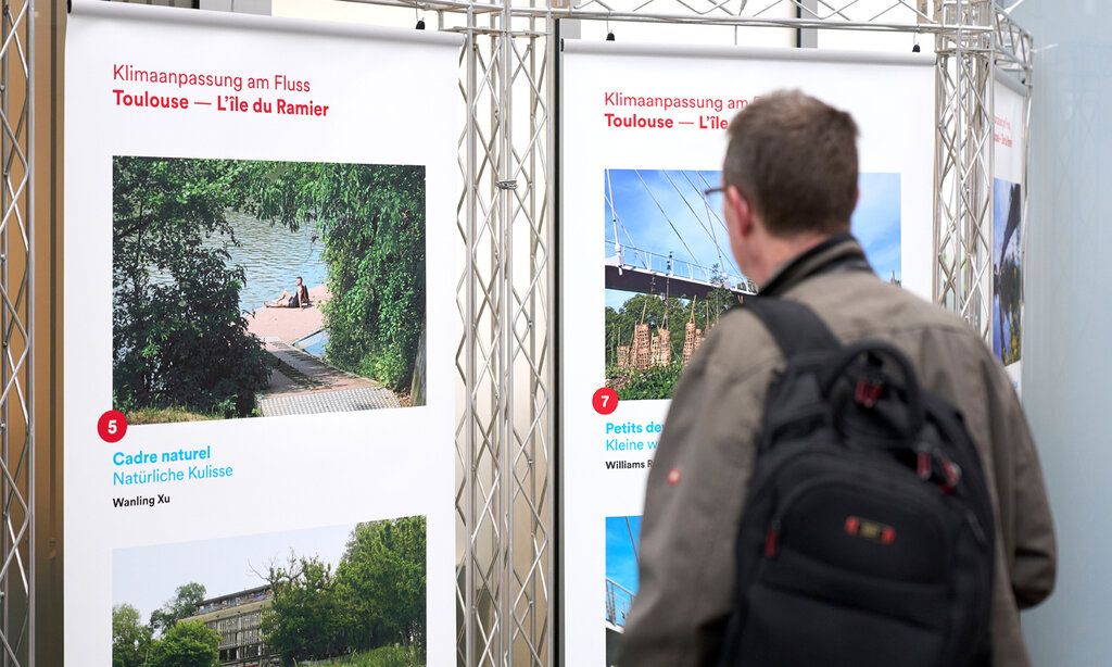 Ausstellung Klimaanpassung am Fluss, Mann steht vor Stellwand und betrachtet Fotoausstellung