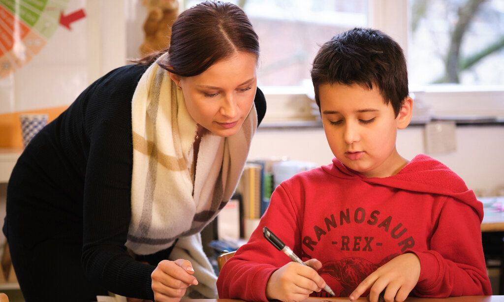 Betreuerin hilft Schüler bei den Hausaufgaben
