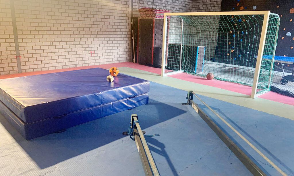 Turnhalle von innen, dicke Matte, Fußballtor, Bälle, keine Menschen