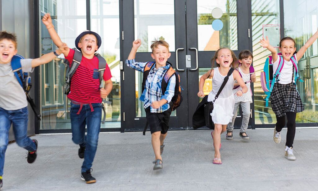 Grundschulkinder laufen jubelnd aus dem Schulgebäude
