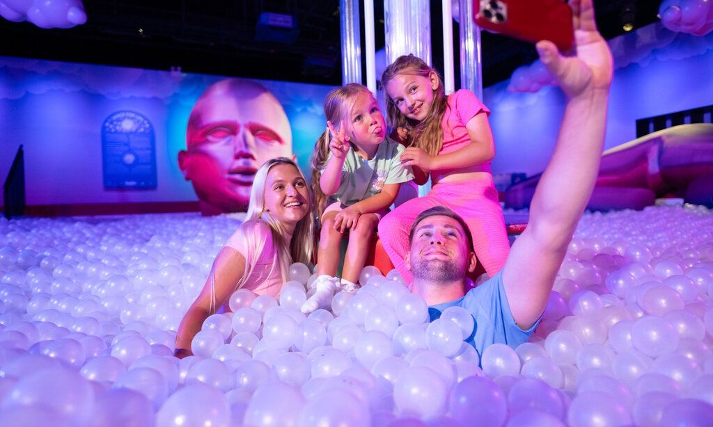 Vater, Mutter und zwei Töchter in einem Bällebad im Bubble Planet