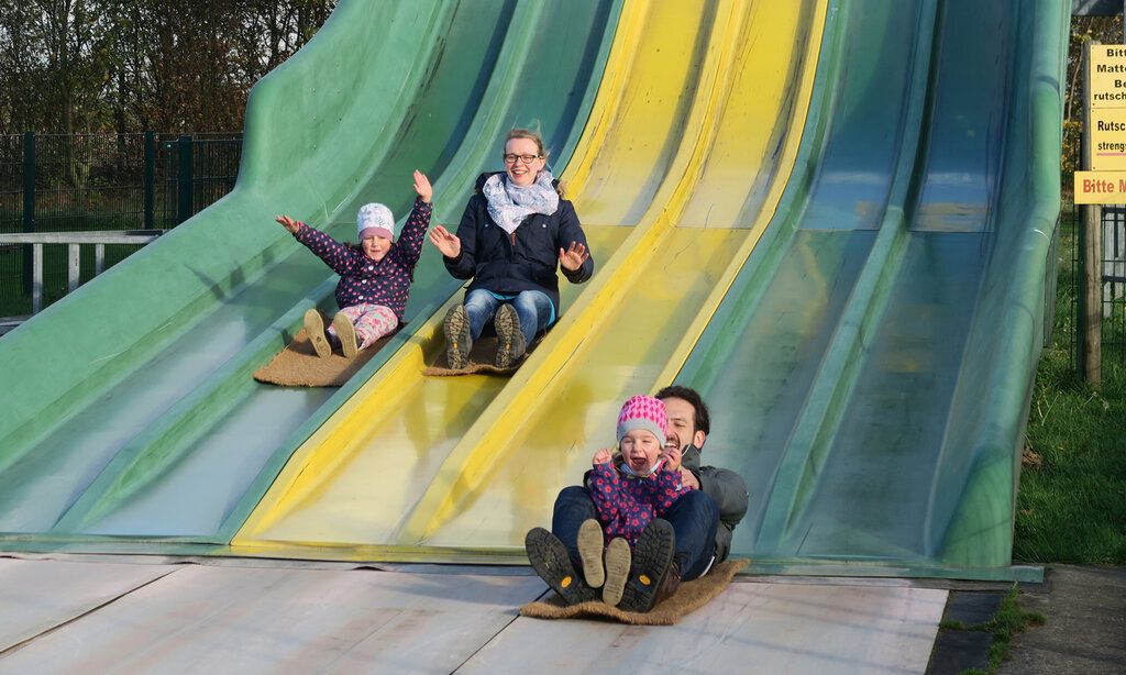 Vater, Mutter und zwei Kinder rutschen auf der Rutschbahn des Bubenheimer Spielelandes