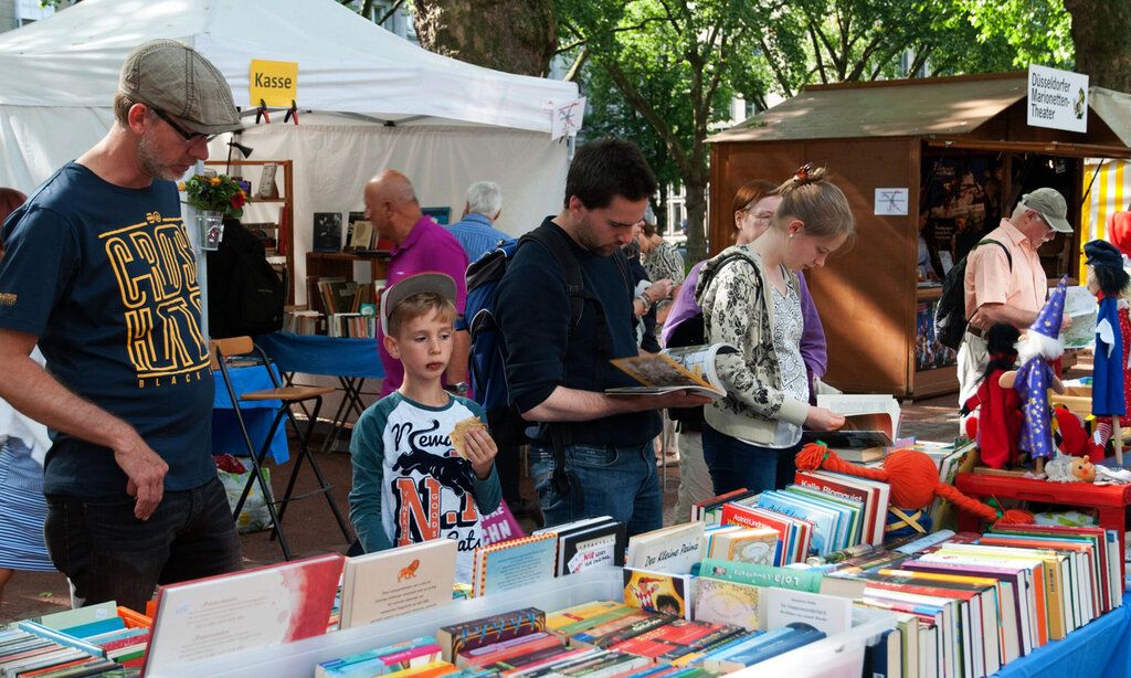 Besucher des Bücherbummels auf der Düsseldorfer Kö zwischen Bücherständen, einige blättern in Büchern