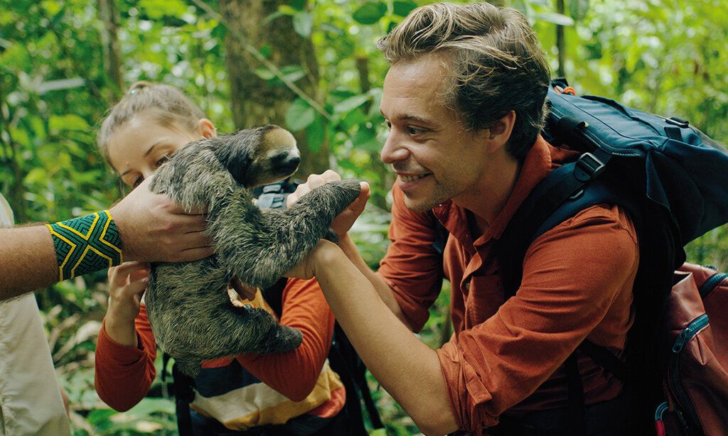 Checker Tobi im Dschungel, ihm wird ein Faultier hingehalten