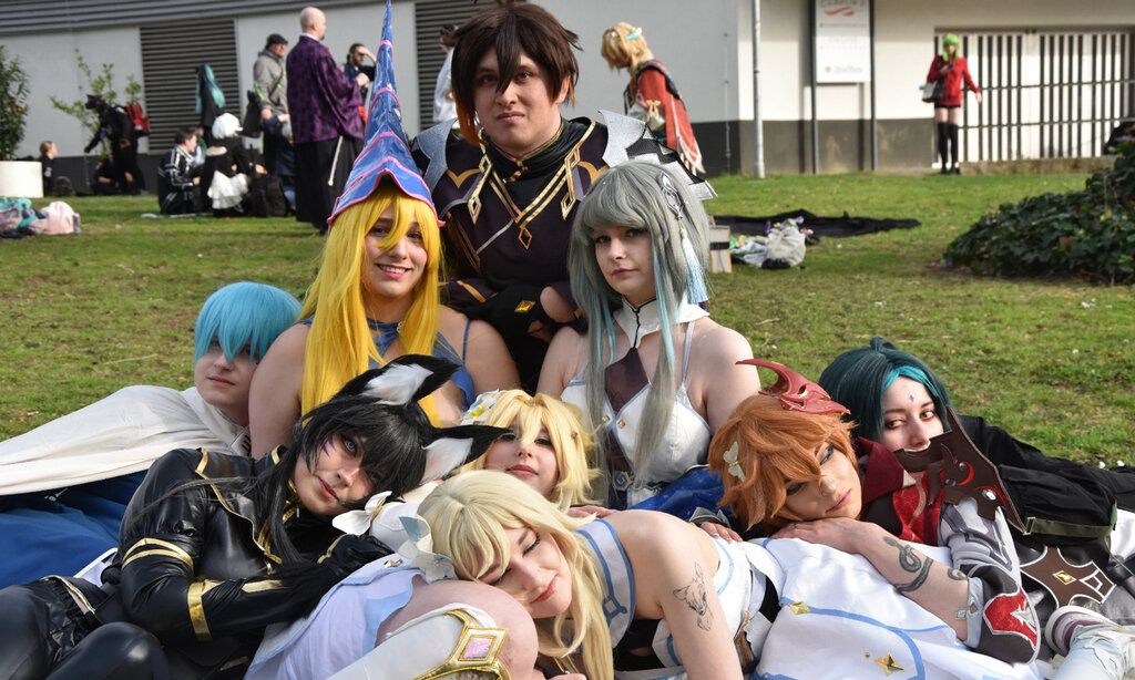 Cosplayer sitzen zusammen auf einer Rasenfläche bei einer Veranstaltung
