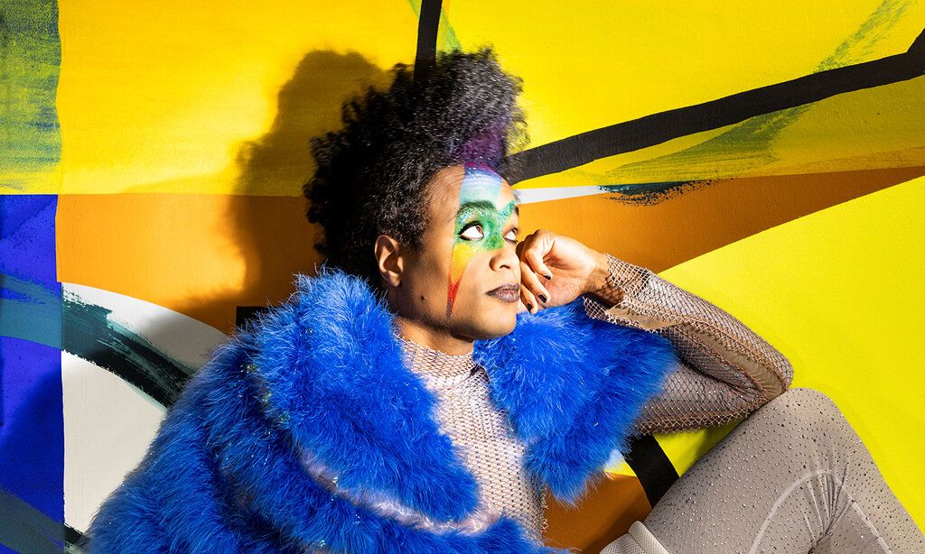 Schaupspieler sitzt vor bunter, gelber Wand   Auf dem Bild Jonathan Gyles