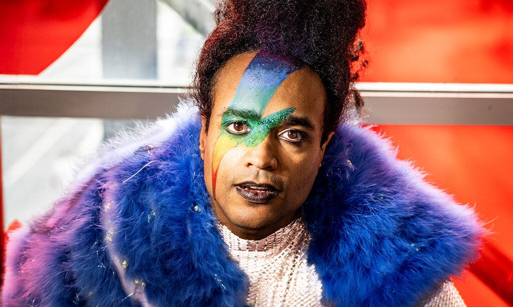 Schauspieler vor roter Wand, Regenbogen-Blitz im Gesicht geschminkt   Auf dem Bild Jonathan Gyles   Foto: Thomas Rabsch