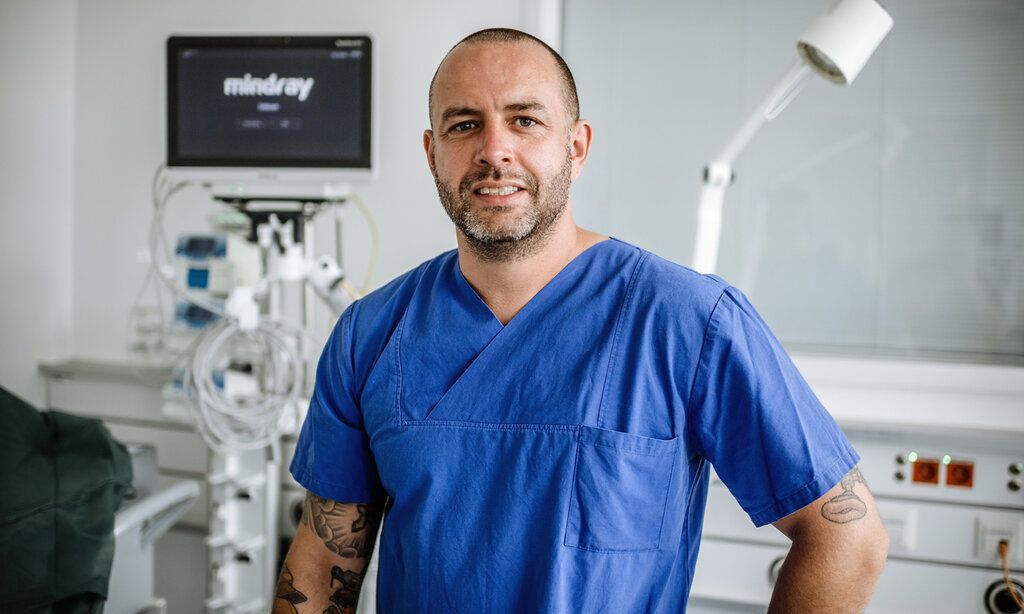 Mann in blauer Pflegerbekleidung in Untersuchungszimmer