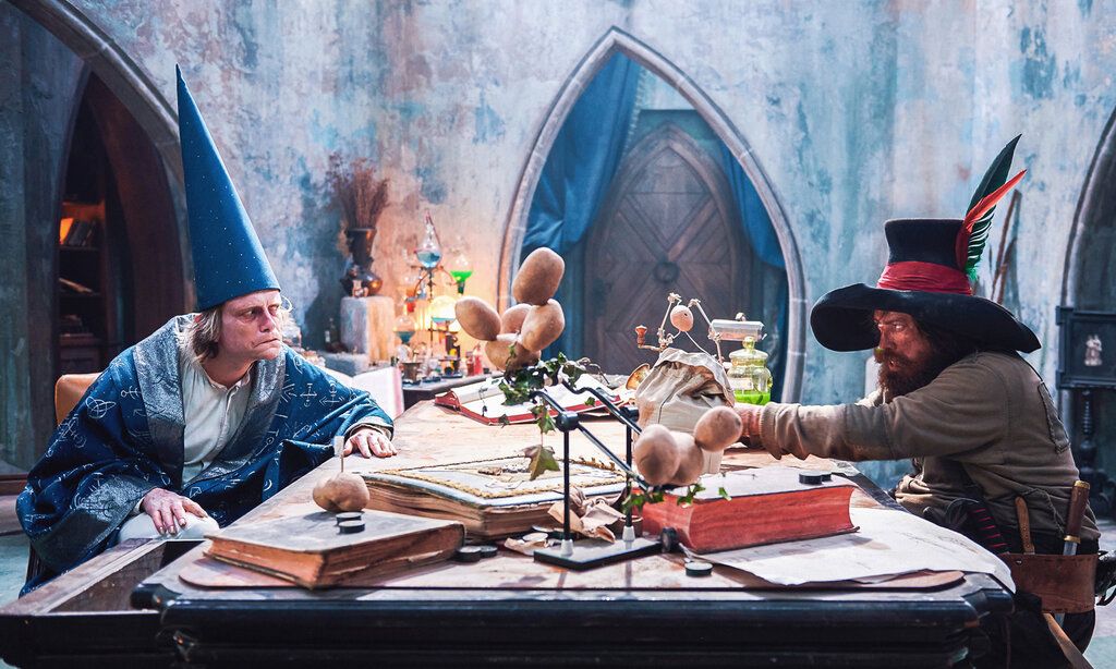 Ein Zauberer und Räuber Hotzenplotz sitzen an einem Schreibtisch und streiten
