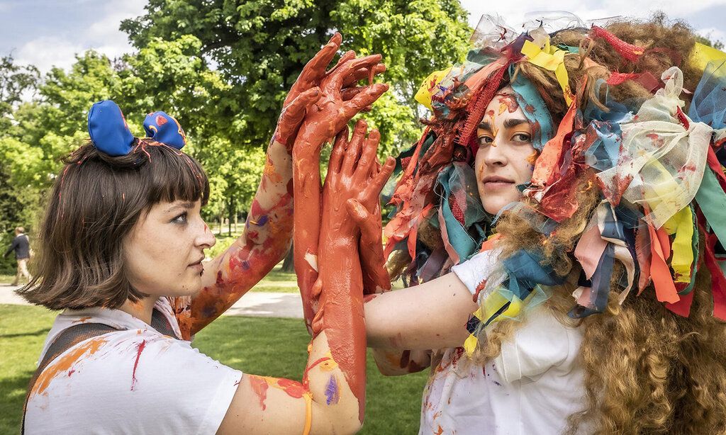 zwei Schauspielerinen, bunt als Löwen verkleidet spielen im Park