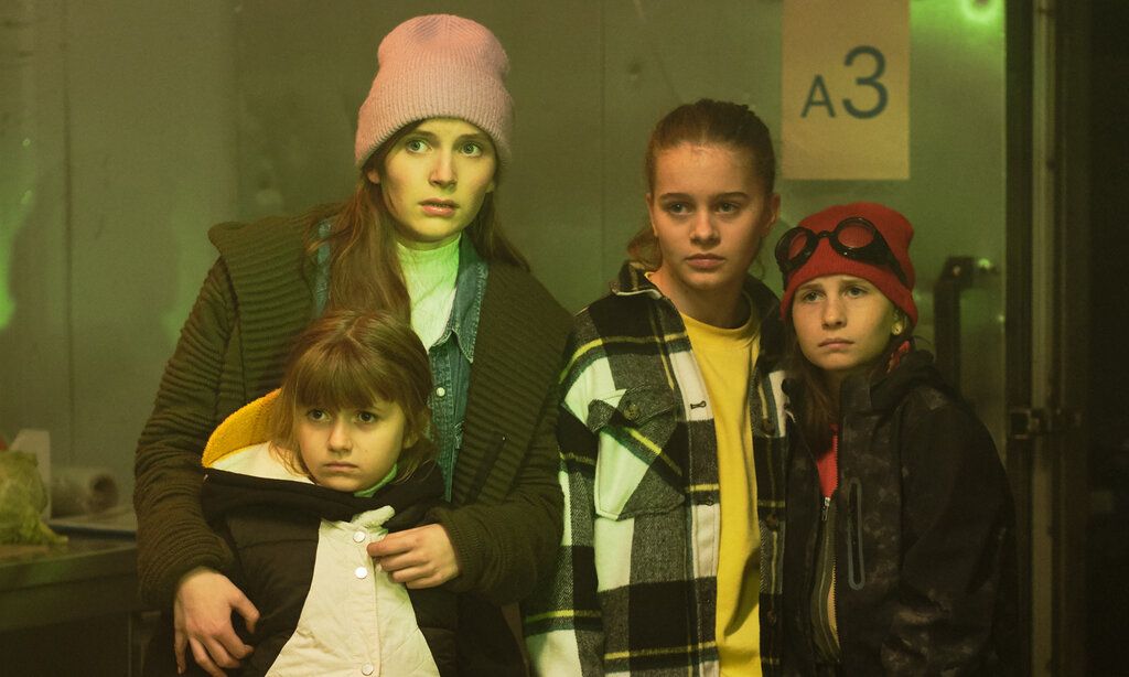 vier Schwestern stehen in einem Raum, der grünlich beleuchtet ist